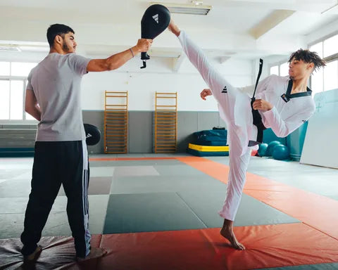 Martial artist practising kicks in adidas combat gear